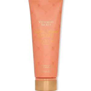Imagen promocional de la loción corporal Victoria's Secret Golden Apricot & Honey de 236 ml sobre una base de mármol, rodeada de albaricoques, un frasco de miel, un dipper de miel y cucharas de madera. Envío gratuito a nivel nacional en Ecuador.