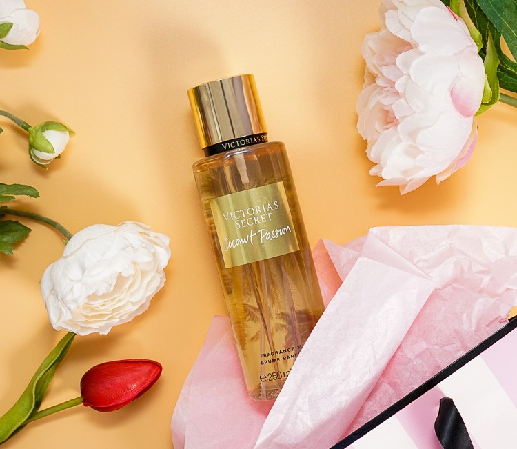 Body mist Victoria's Secret Coconut Passion de 250 ml en flat lay con flores blancas y papel de seda rosa.