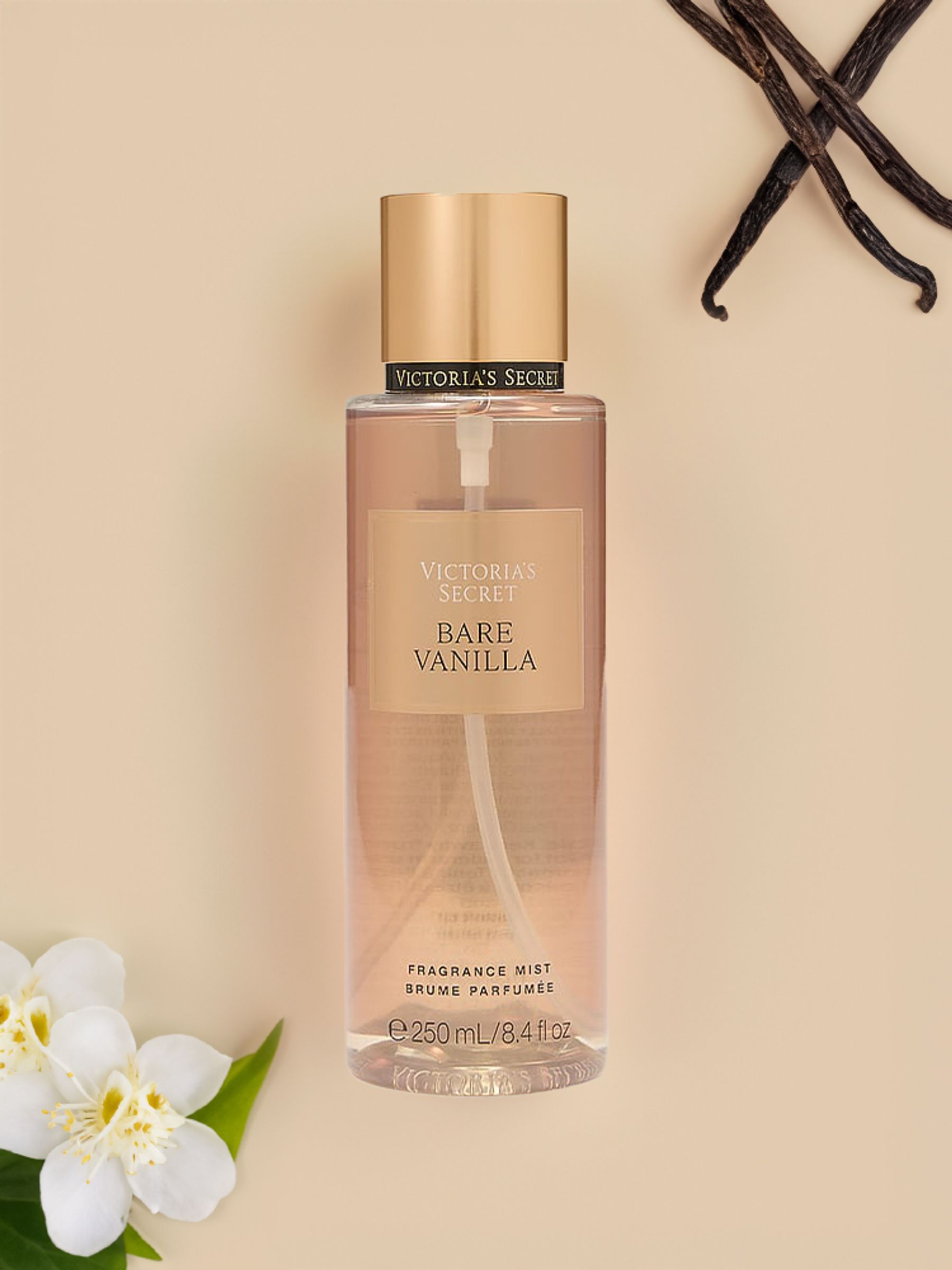 Body mist Victoria's Secret Bare Vanilla de 250 ml con vainas de vainilla y flores blancas sobre fondo beige.