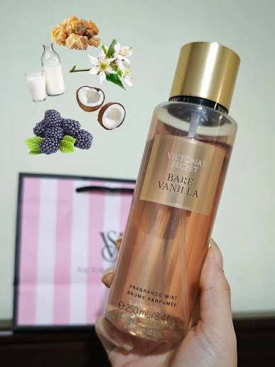 Mano sosteniendo el body mist Victoria's Secret Bare Vanilla de 250 ml con infografía de ingredientes como coco, moras y vainilla.