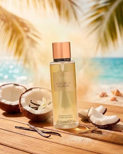 Body mist Victoria's Secret Coconut Passion de 250 ml sobre mesa de madera con cocos, vainilla y fondo de playa.