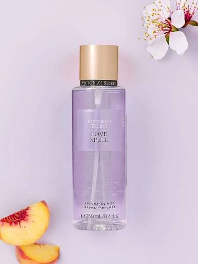 Body mist Victoria's Secret Love Spell de 250 ml junto a duraznos y flor de cerezo.