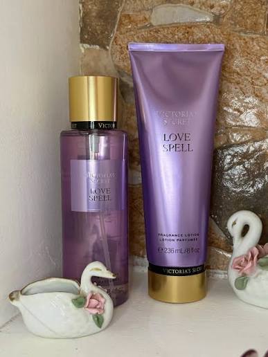 Set Victoria's Secret Love Spell sobre repisa con figuras de cisnes de cerámica.