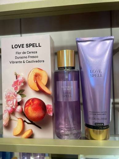 Set Victoria's Secret Love Spell con caja, body mist y loción sobre estante de tienda.