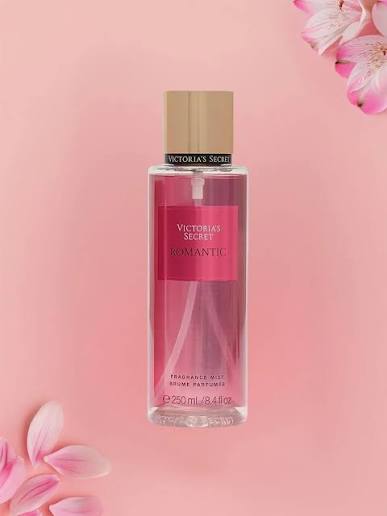 Frasco de mist corporal Victoria's Secret Romantic de 250 ml sobre fondo rosa con flores de cerezo.