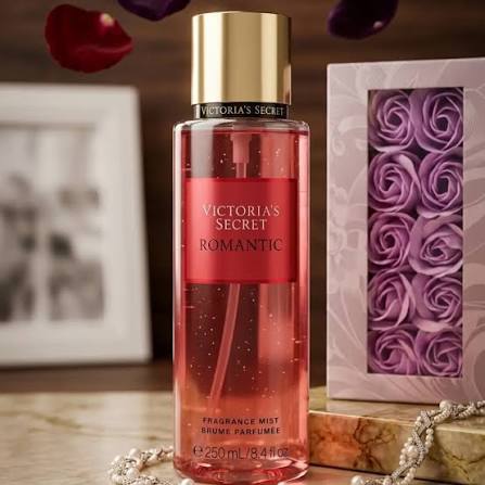 Botella de mist corporal Victoria's Secret Romantic de 250 ml junto a una caja decorativa de rosas moradas.